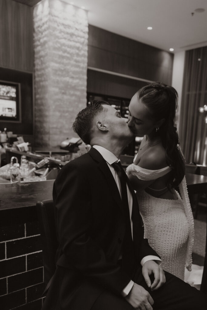 The couple sharing a romantic kiss at the hotel bar during their Austin engagement session surrounded by moody lighting and a cozy atmosphere